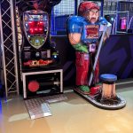 Combo Boxer arcade boxing game with a muscular coach figure and a red LED score display in an arcade.