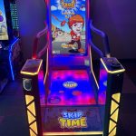 Front view of a bright arcade game cabinet titled 'Skip Time' with neon yellow/blue edges and a cartoon hero on the screen (Single Player).