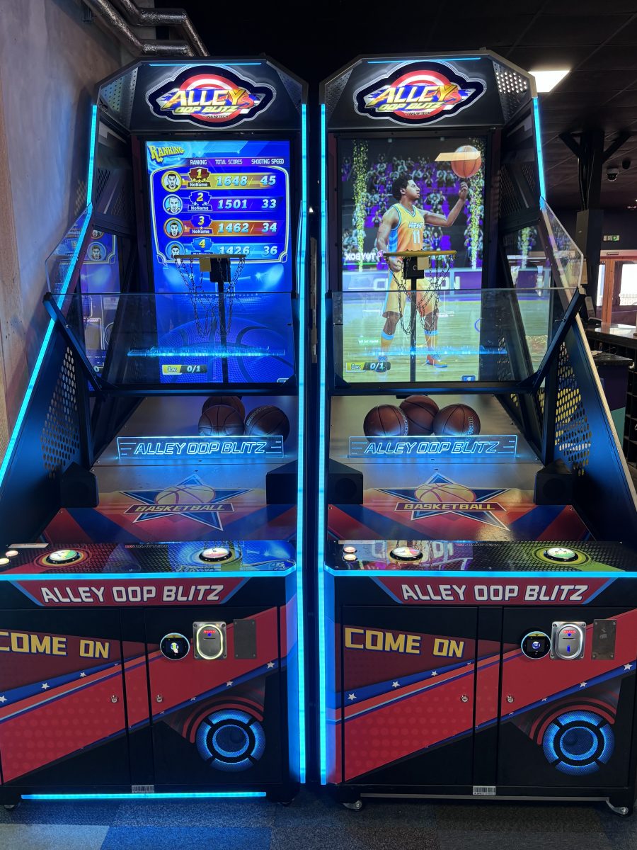 Pair of Alley Oop Blitz arcade basketball machines with blue neon lighting and hoops, facing forward in a gaming arcade.